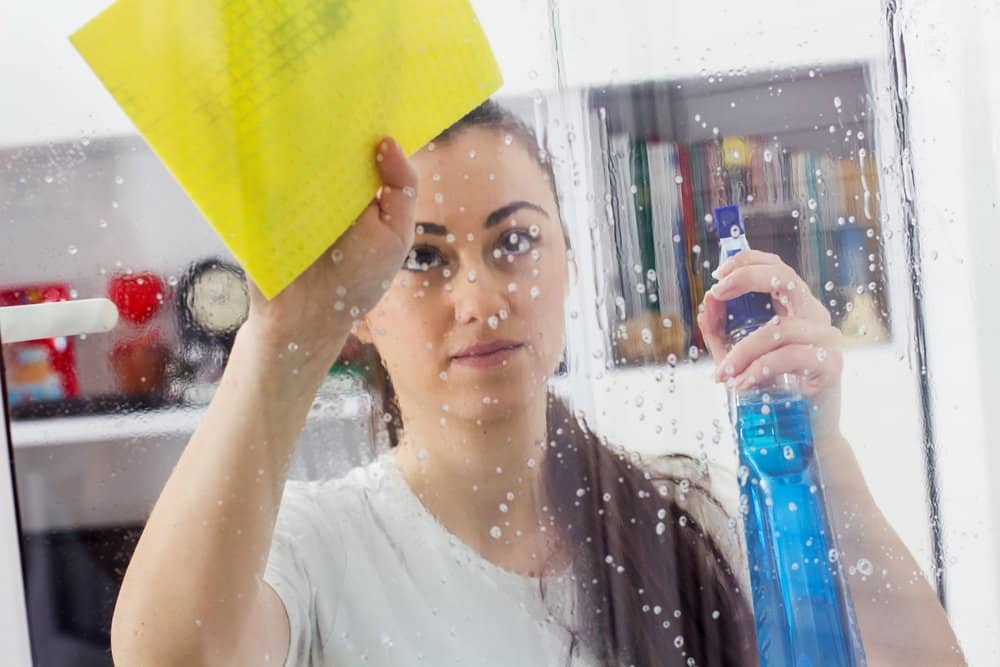 Junge Frau beim Fensterputzen ohne Fensterputzgerät