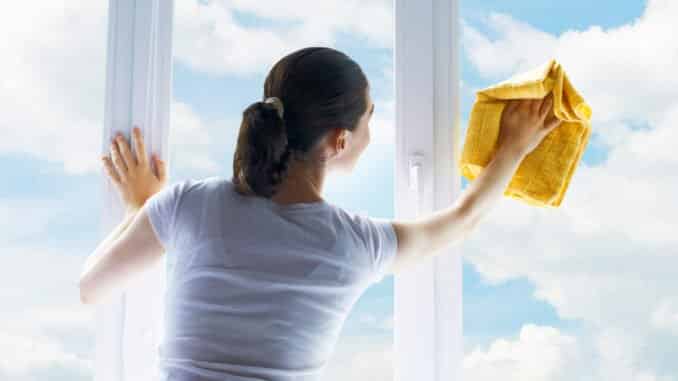 Junge Frau putzt Fenster