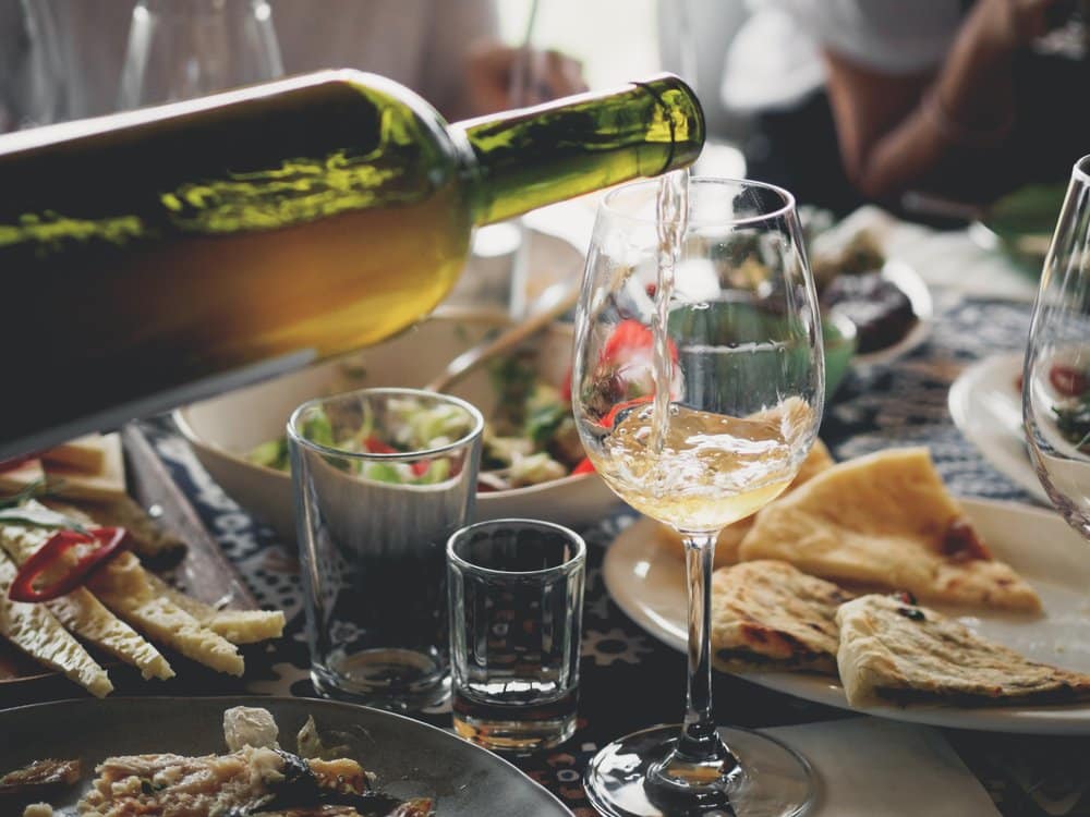 Gedeckter Tisch mit Speisen und einer Flasche Weißwein