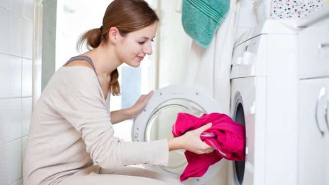 Junge Frau hockt vor Waschmaschine ohne Waschmaschinenpodest