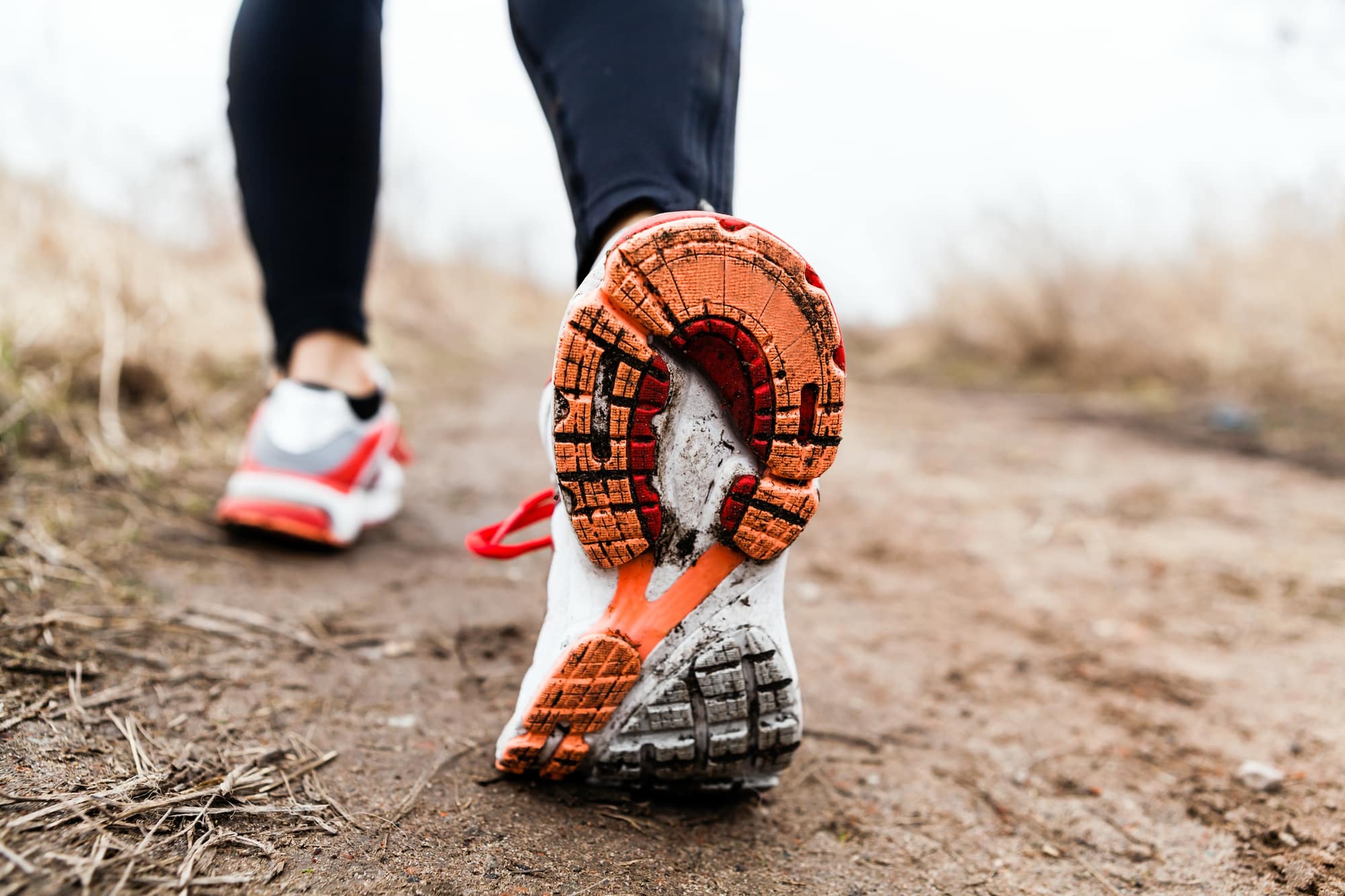 Verschmutzte Laufschuhsohle auf einem schlammigen Feldweg