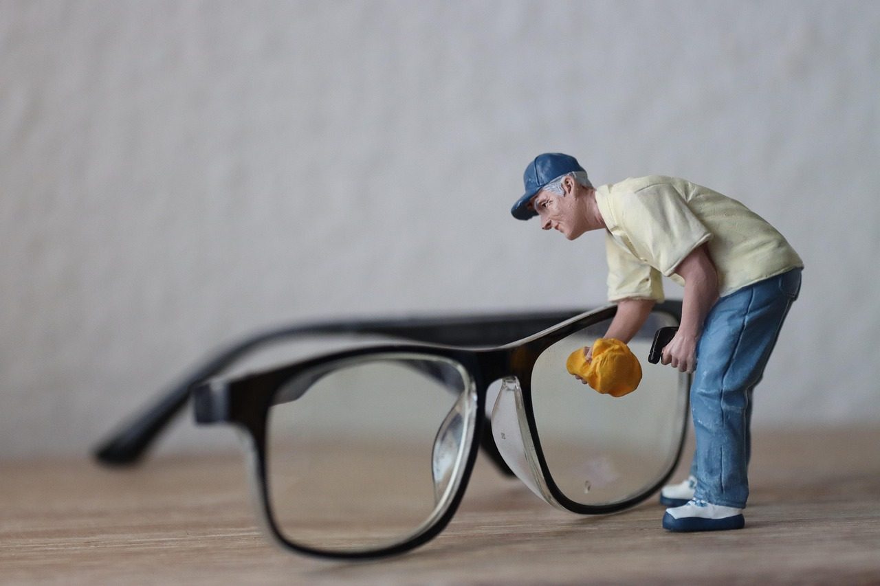 Miniaturfigur mit Putztuch steht vor einer schwarzen Brille