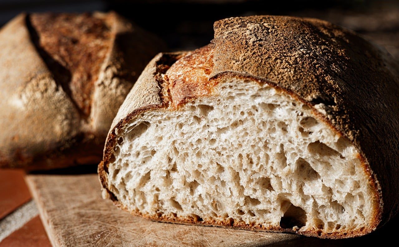 Angeschnittener Laib Sauerteigbrot mit grober Krume auf einem Holzbrett