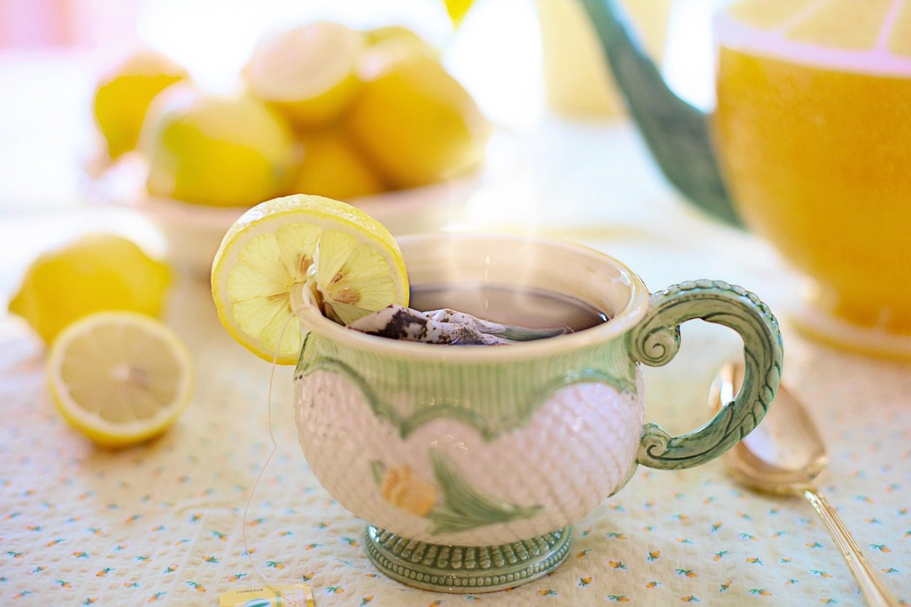 Tasse mit heißem Getränk und Zitronenscheibe, daneben halbierte Zitronen