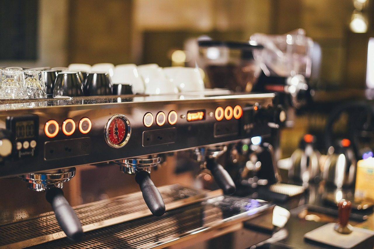 Siebträgermaschine mit mehreren Brühgruppen und Tassen in einem Café
