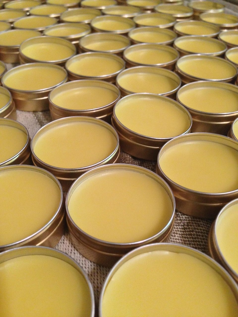 Viele runde Blechdosen, gefüllt mit gelbem Balsam