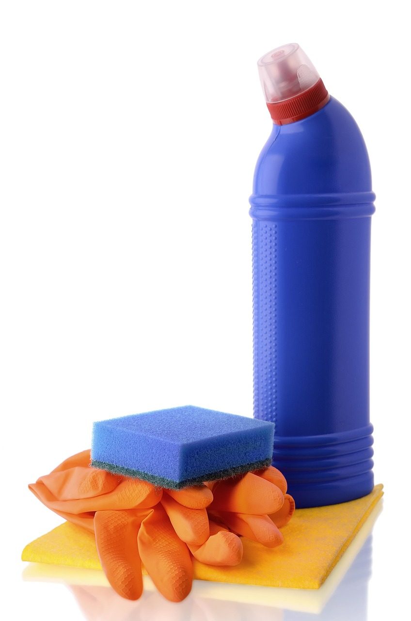 Blaue Reinigerflasche mit Schwamm und orangefarbenen Gummihandschuhen