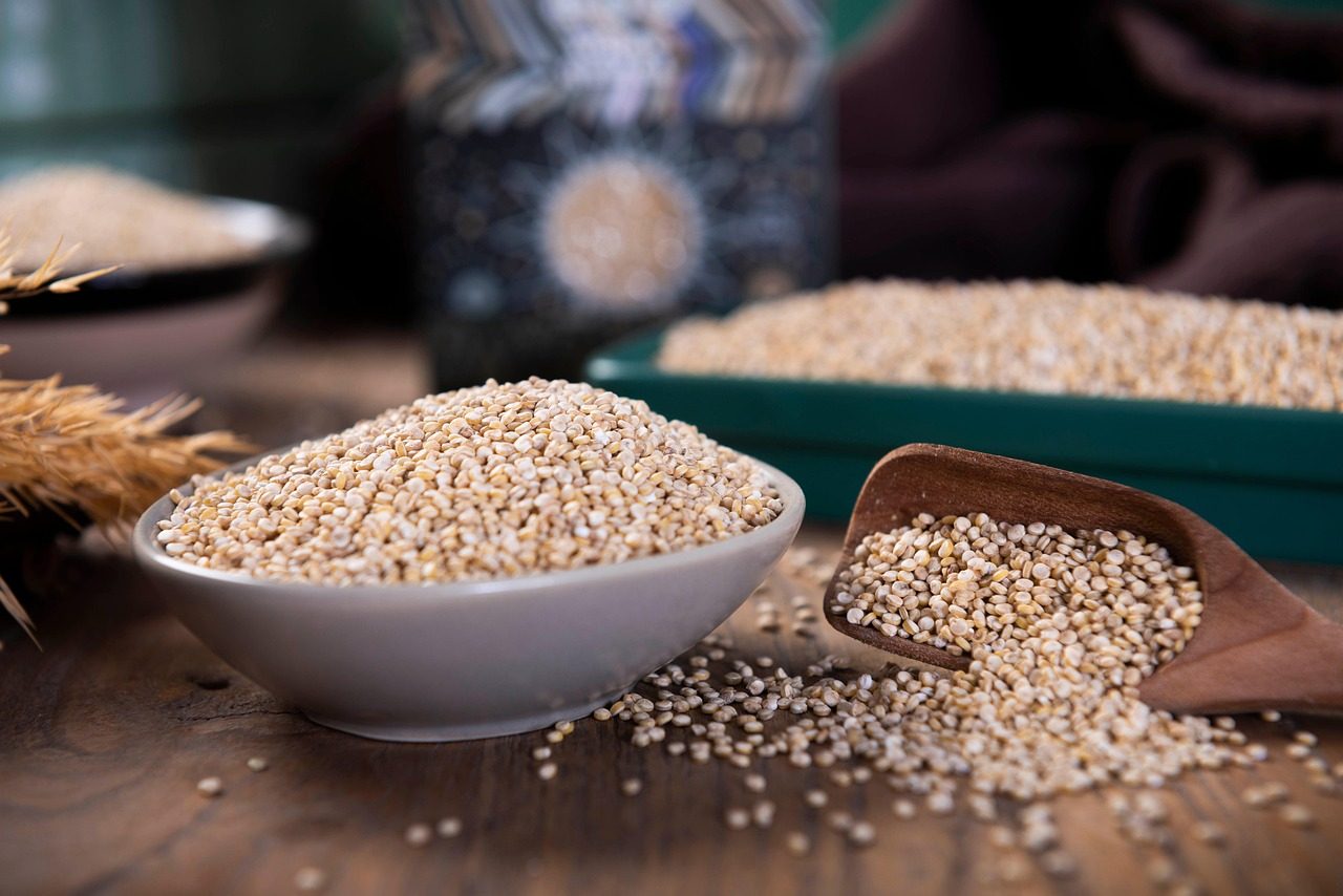 Schale mit hellen Quinoakörnern, daneben eine Schaufel mit Quinoa