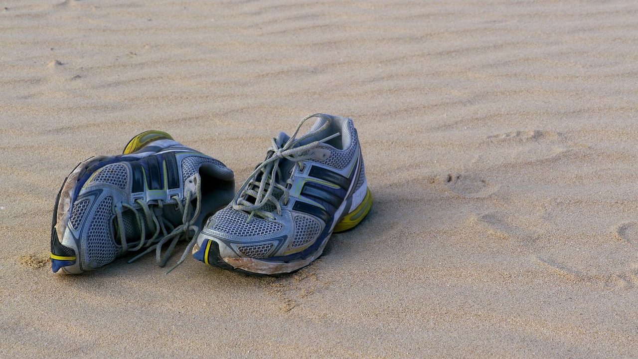 Ein Paar getragene Laufschuhe steht im Sand