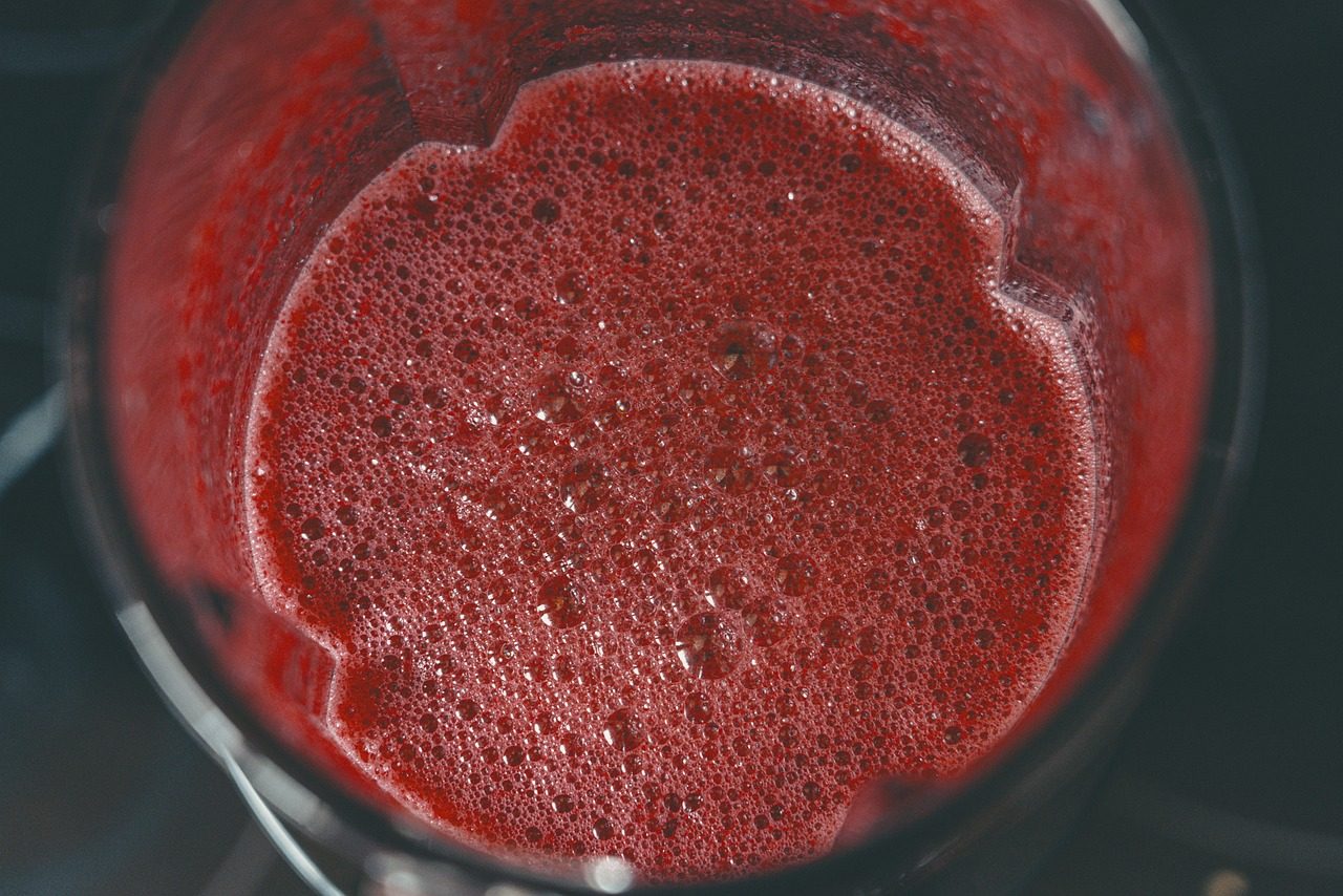 Blick von oben in einen Mixbehälter mit rotem, schaumigem Saft