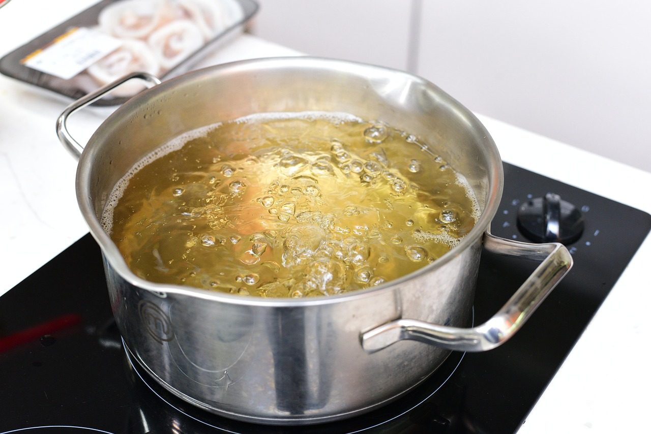 Edelstahltopf mit kochendem Wasser auf einem Kochfeld