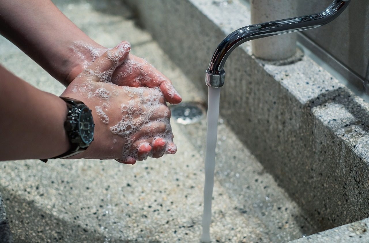 Hände werden unter einem dünnen Wasserstrahl gewaschen