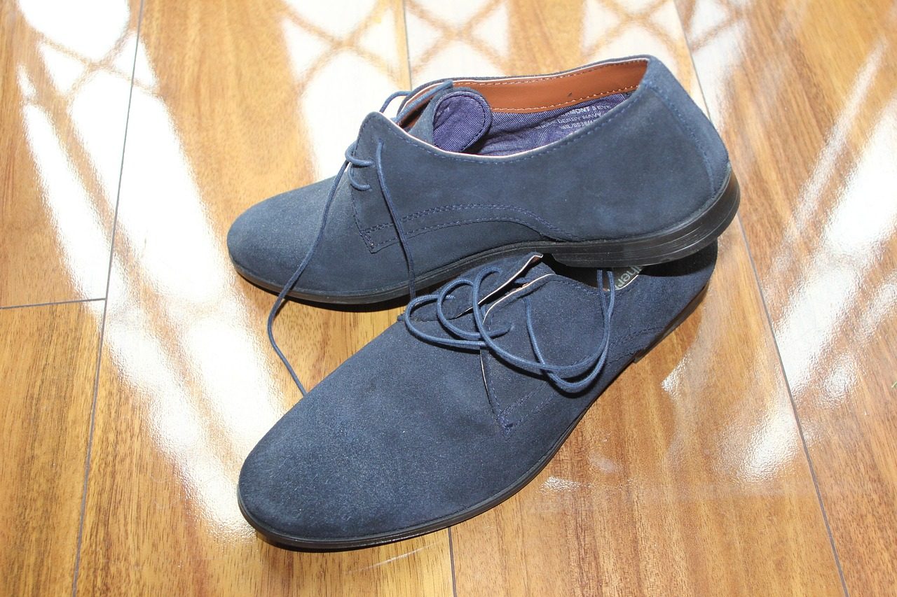 Paar blaue Wildlederschuhe mit Schnürsenkeln auf einem Holzboden