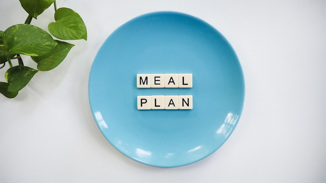 Blauer Teller mit den Wörtern „Meal Plan“ aus Buchstabensteinen